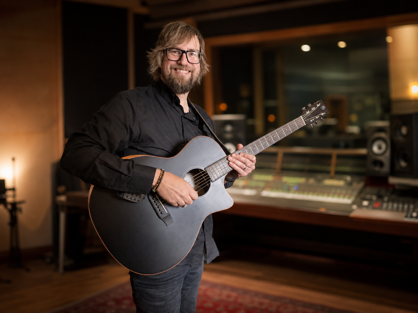Cliff Ward holding an acoustic guitar in a recording studio