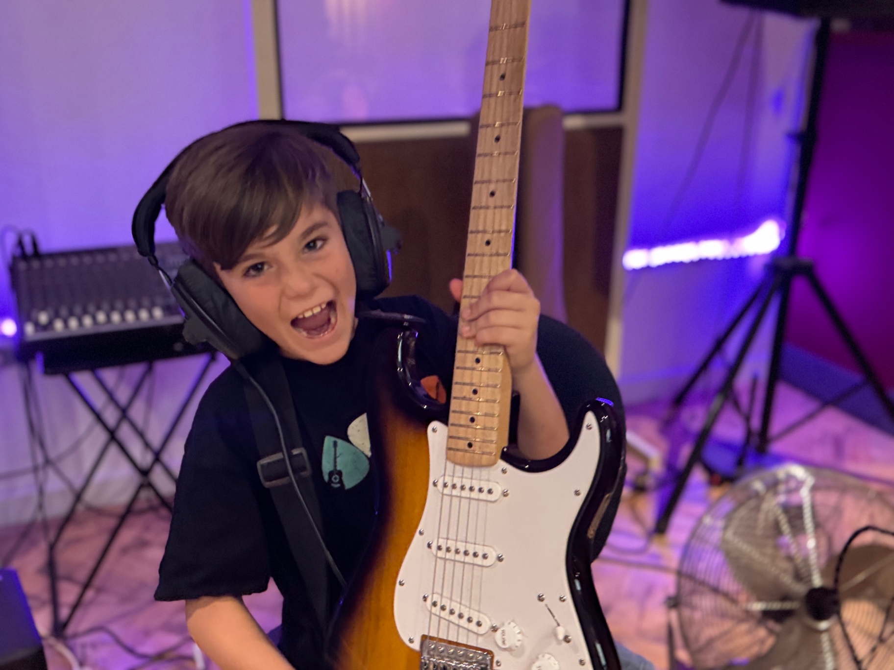 Young guitarist in headphones with a Stratocaster