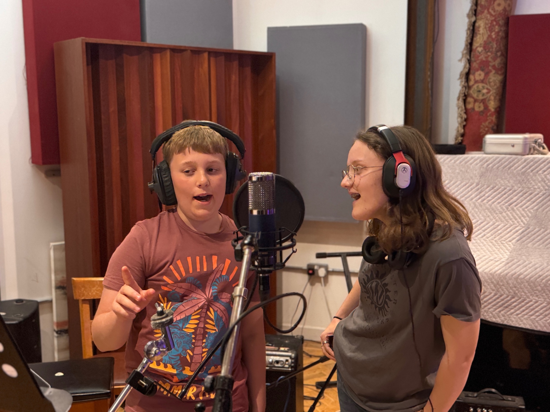 Two students recording vocals at the studio microphone